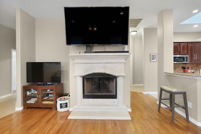 living room with a skylight and light hardwood / wood-style flooring