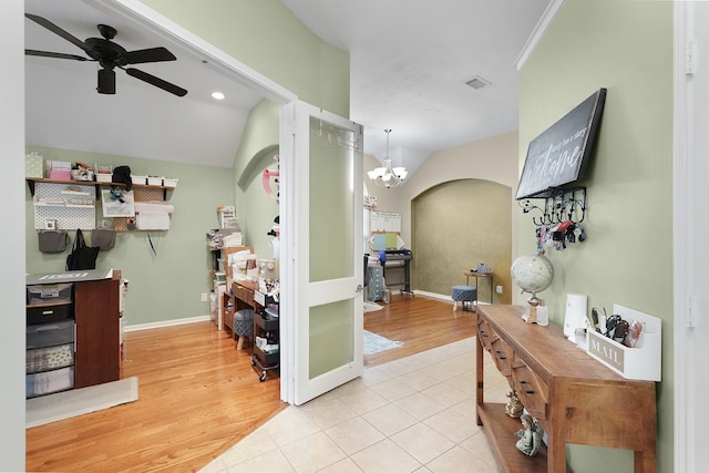 tiled foyer entrance featuring ceiling fan with notable chandelier and vaulted ceiling