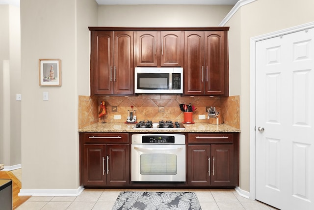 kitchen featuring light stone countertops, appliances with stainless steel finishes, tasteful backsplash, dark brown cabinetry, and light tile floors