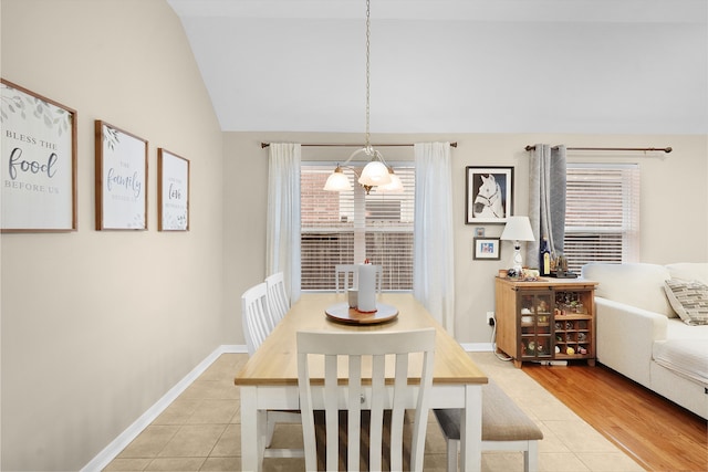 tiled dining area with vaulted ceiling and an inviting chandelier