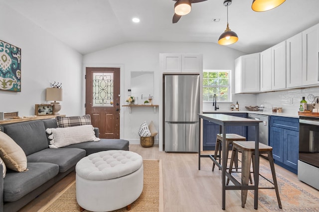 living room with lofted ceiling, ceiling fan, sink, and light hardwood / wood-style floors