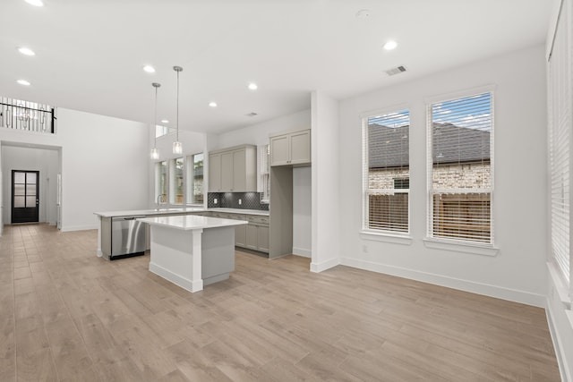 kitchen featuring stainless steel dishwasher, pendant lighting, a center island, tasteful backsplash, and gray cabinets