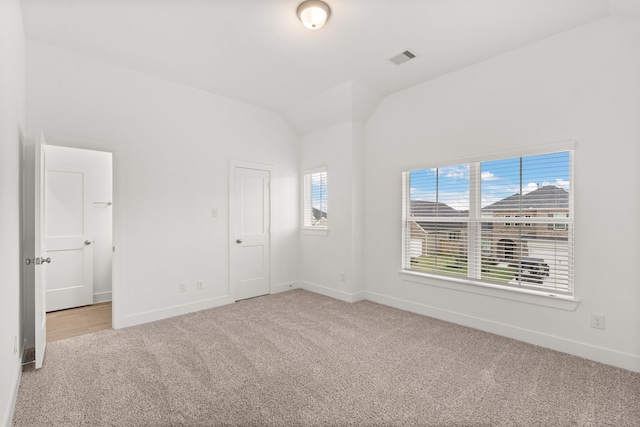 unfurnished bedroom with vaulted ceiling, light carpet, and a closet