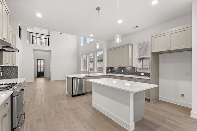 kitchen with hanging light fixtures, stainless steel appliances, tasteful backsplash, a kitchen island, and sink