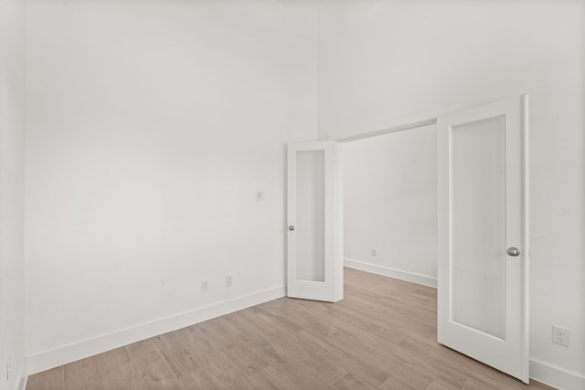 unfurnished room featuring french doors and light hardwood / wood-style flooring