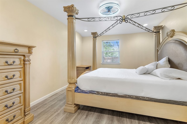 bedroom with hardwood / wood-style floors and ornate columns