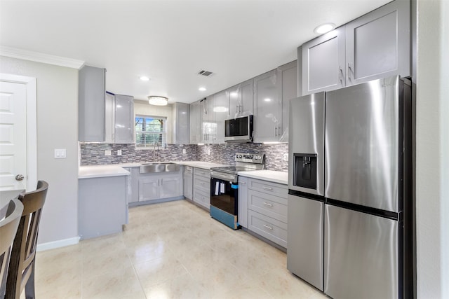 kitchen featuring decorative backsplash, ornamental molding, gray cabinetry, light tile patterned floors, and stainless steel appliances