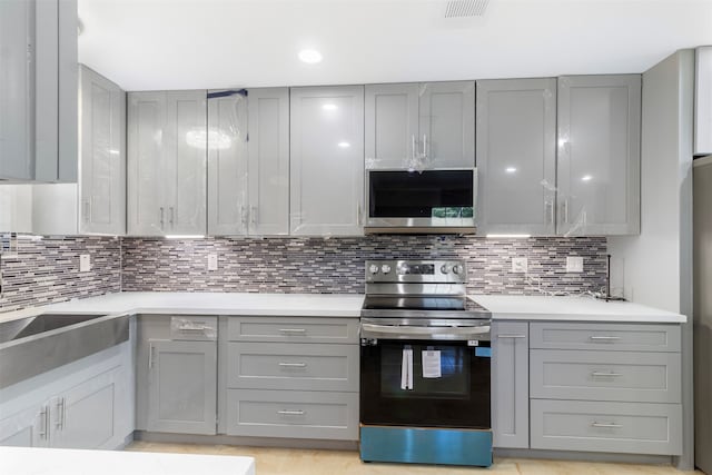 kitchen featuring gray cabinetry, backsplash, and appliances with stainless steel finishes