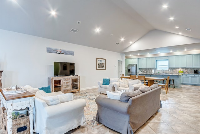 living room featuring light tile floors, high vaulted ceiling, and sink