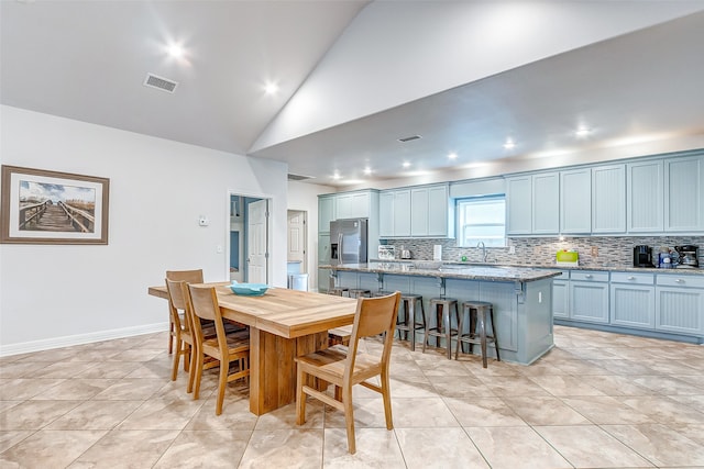 tiled dining room featuring high vaulted ceiling and sink