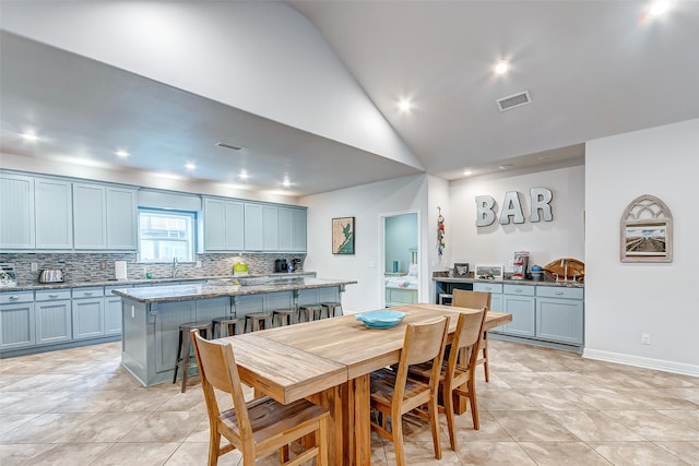 dining area with light tile flooring, sink, and lofted ceiling