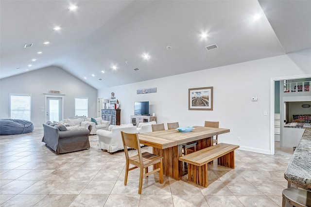 dining area featuring light tile floors and high vaulted ceiling