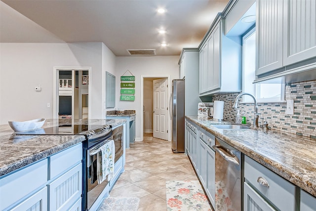 kitchen with stainless steel appliances, light tile floors, sink, gray cabinets, and stone countertops