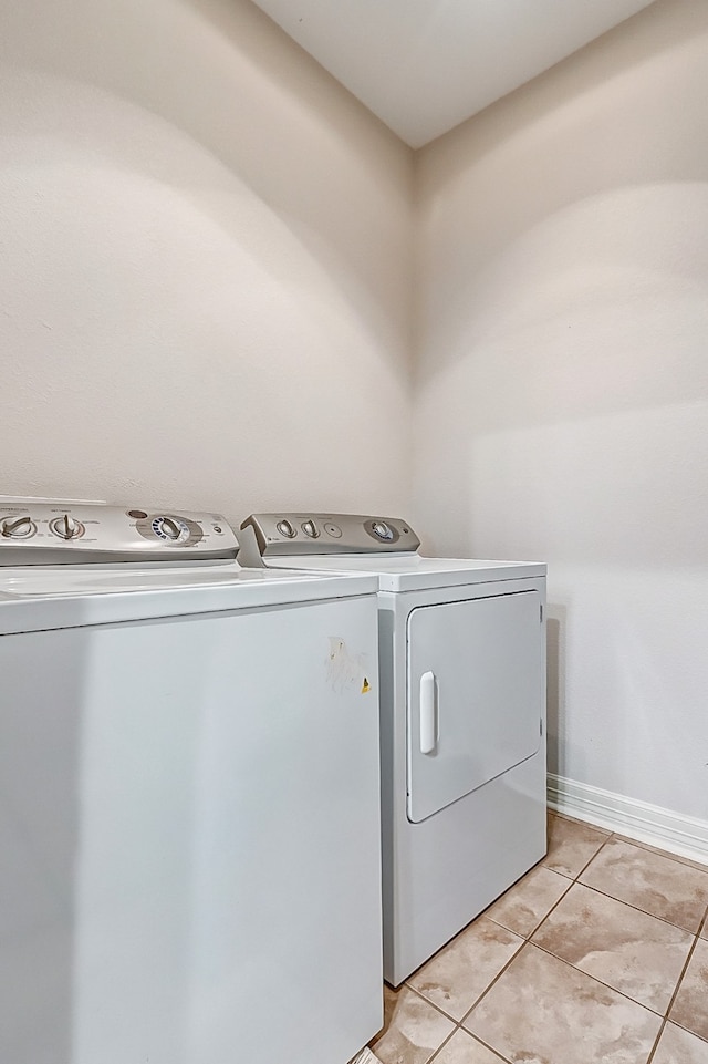 clothes washing area with separate washer and dryer and light tile flooring