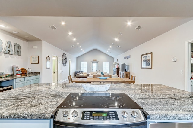 kitchen with stove, dark stone countertops, a center island, and vaulted ceiling