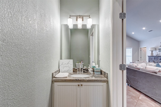 bathroom with tile flooring, vaulted ceiling, and vanity with extensive cabinet space