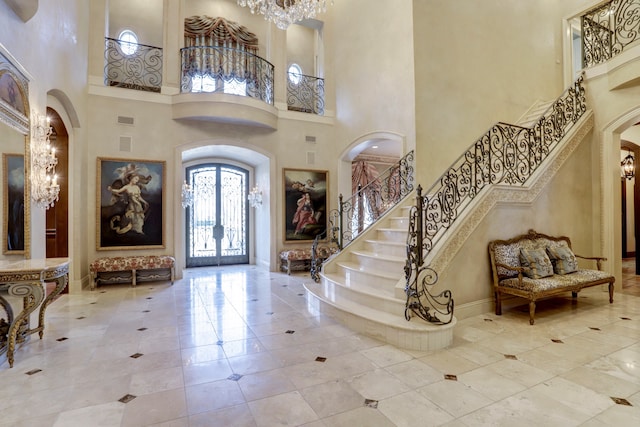 foyer entrance featuring a towering ceiling, a notable chandelier, and light tile floors