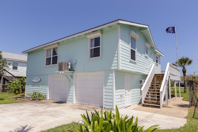 view of front of property featuring a garage, driveway, central AC, and stairs