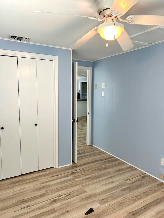 unfurnished bedroom with light wood finished floors, visible vents, ceiling fan, ornamental molding, and a closet