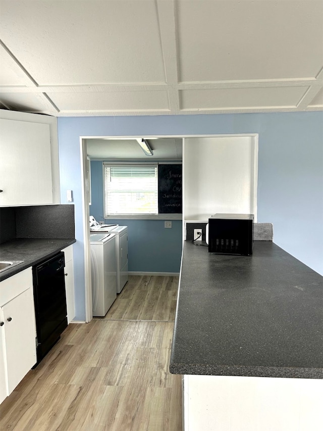 kitchen featuring black appliances, light wood-style flooring, dark countertops, white cabinetry, and washing machine and clothes dryer