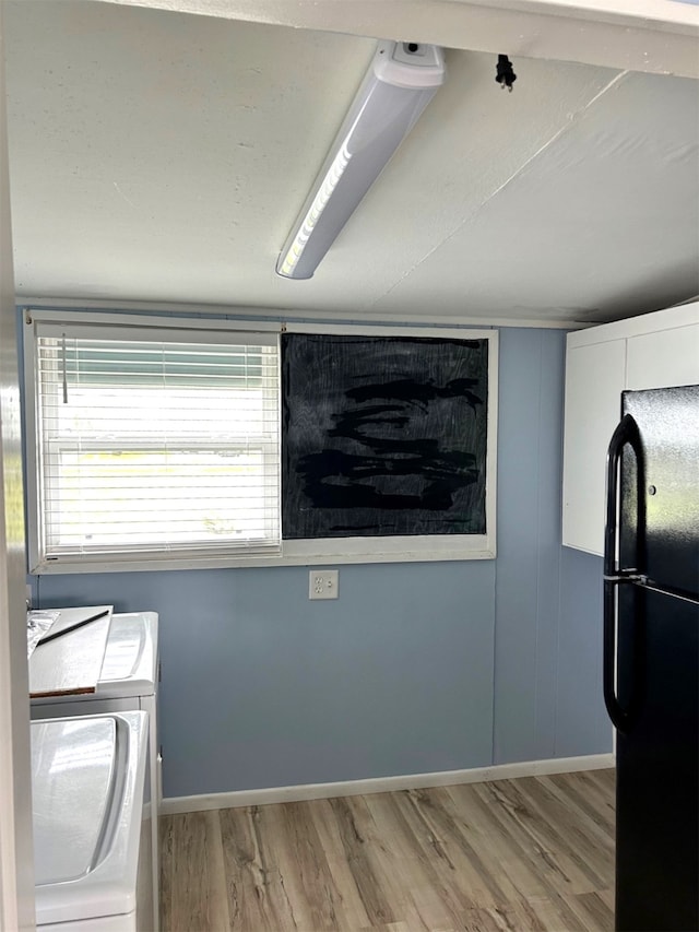 washroom with washing machine and dryer, light wood-type flooring, and baseboards