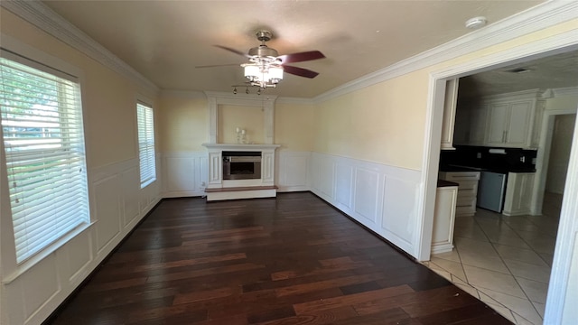 unfurnished living room featuring tile floors, crown molding, and ceiling fan