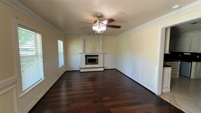 unfurnished living room featuring ornamental molding, dark wood-type flooring, and ceiling fan