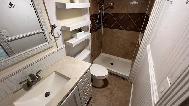 bathroom with tiled shower, tile flooring, vanity, and toilet