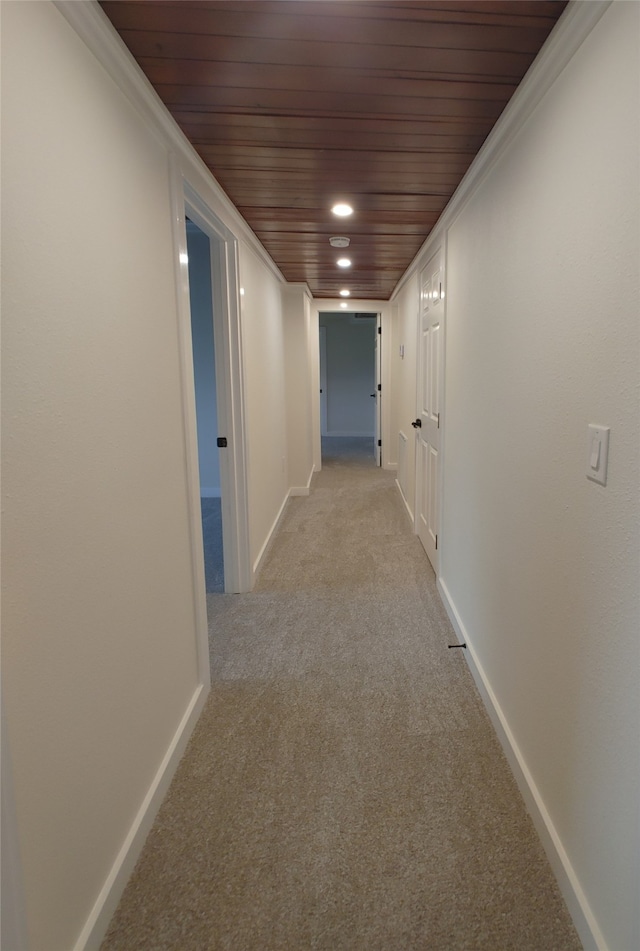 hallway featuring wood ceiling, light colored carpet, and ornamental molding