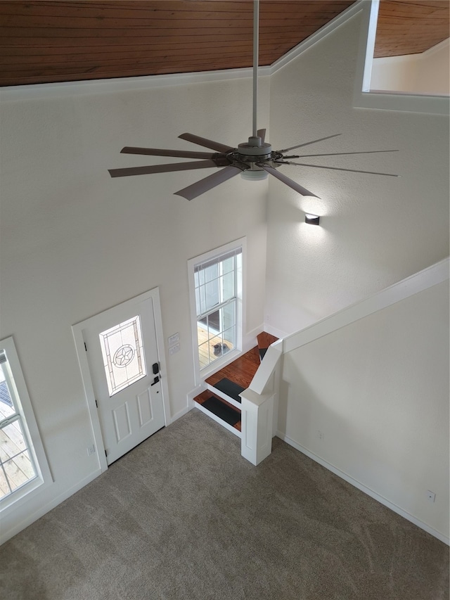 entryway featuring wood ceiling, a healthy amount of sunlight, and dark carpet