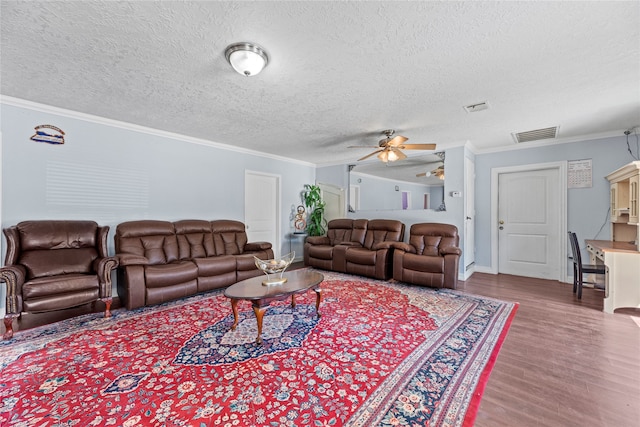 living room with ornamental molding, wood-type flooring, ceiling fan, and a textured ceiling