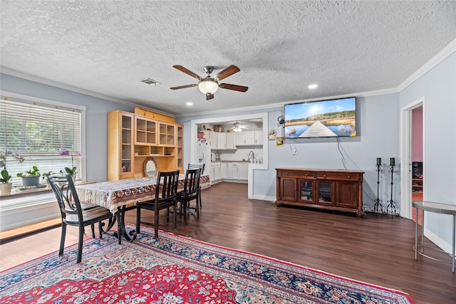 dining area featuring ceiling fan, a textured ceiling, sink, dark hardwood / wood-style floors, and ornamental molding