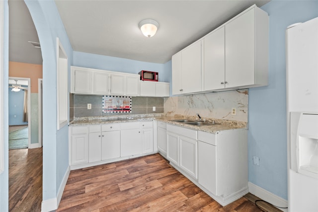 kitchen with backsplash, ceiling fan, hardwood / wood-style flooring, white cabinets, and sink