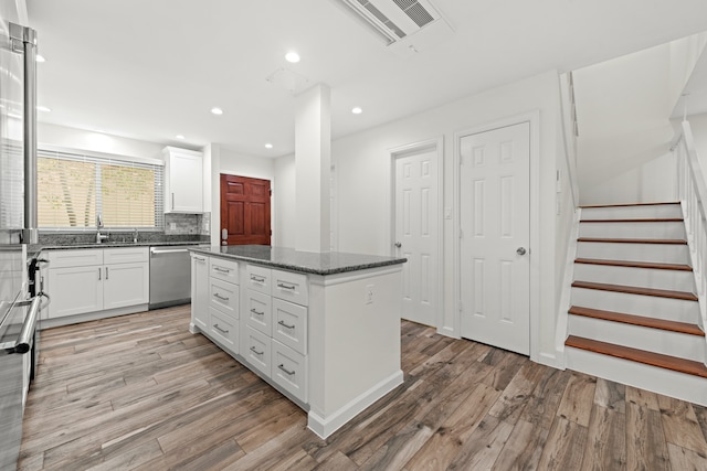 kitchen with dishwasher, light hardwood / wood-style floors, white cabinetry, and a kitchen island