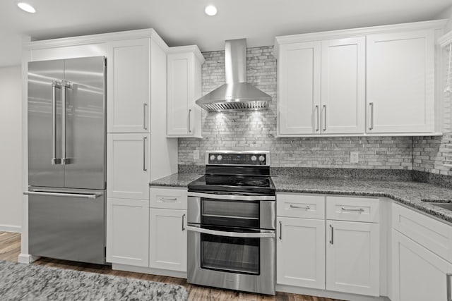 kitchen featuring light wood-type flooring, white cabinets, wall chimney range hood, decorative backsplash, and stainless steel appliances