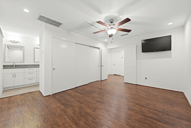 unfurnished bedroom featuring connected bathroom, ceiling fan, dark wood-type flooring, and sink