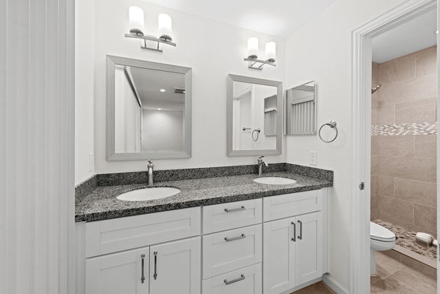 bathroom with vanity, tile patterned flooring, toilet, and tiled shower