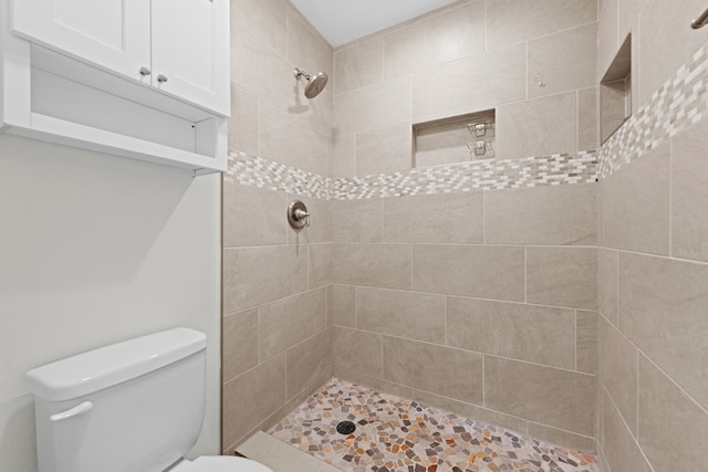 bathroom featuring tiled shower and toilet