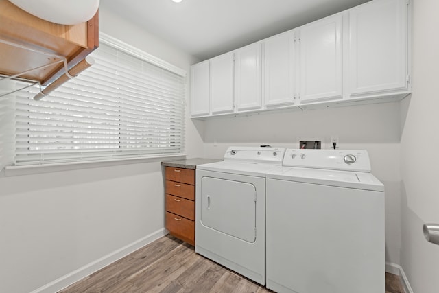 clothes washing area with light hardwood / wood-style flooring, cabinets, and washer and dryer