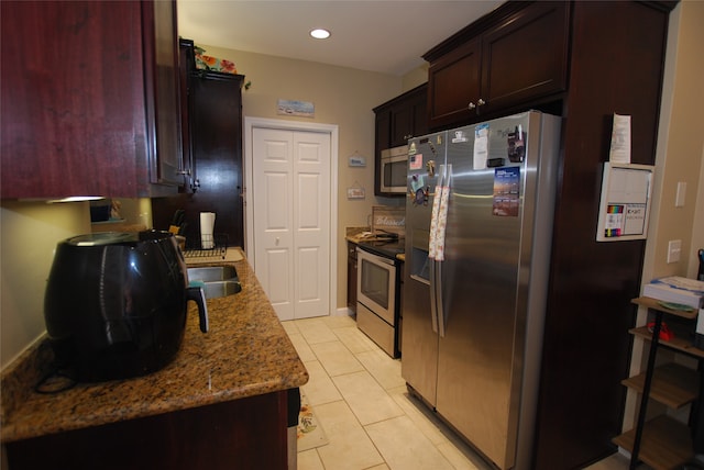 kitchen featuring stainless steel appliances, light tile floors, and light stone countertops