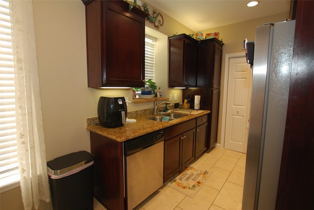 kitchen with light tile flooring, stainless steel appliances, sink, light stone counters, and dark brown cabinetry