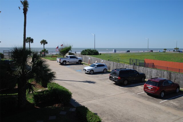 view of parking with a lawn and a water view