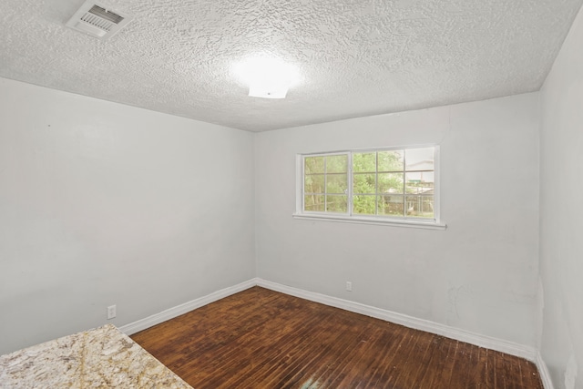 empty room featuring dark wood-type flooring and a textured ceiling