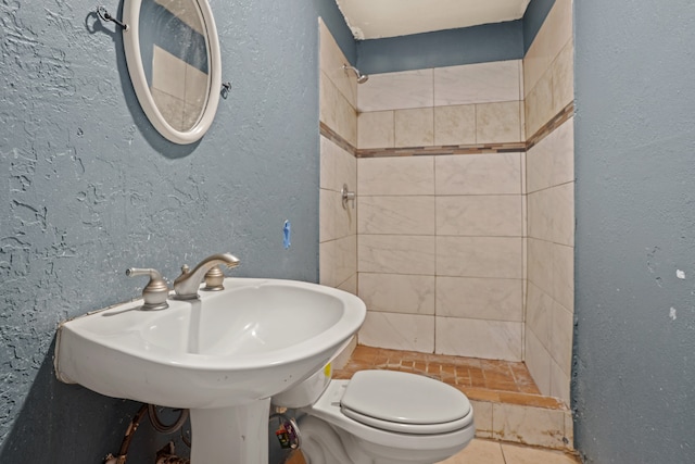 bathroom featuring tiled shower and toilet