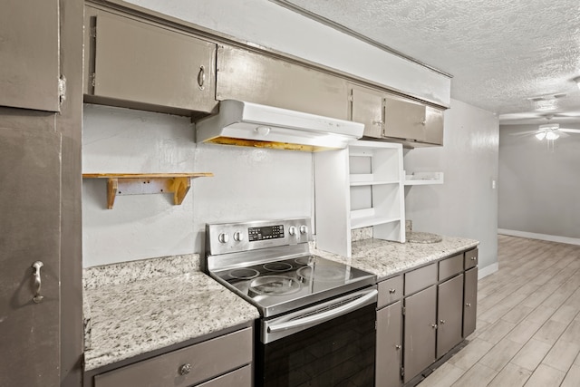 kitchen with light stone countertops, ceiling fan, light hardwood / wood-style floors, stainless steel electric range, and a textured ceiling