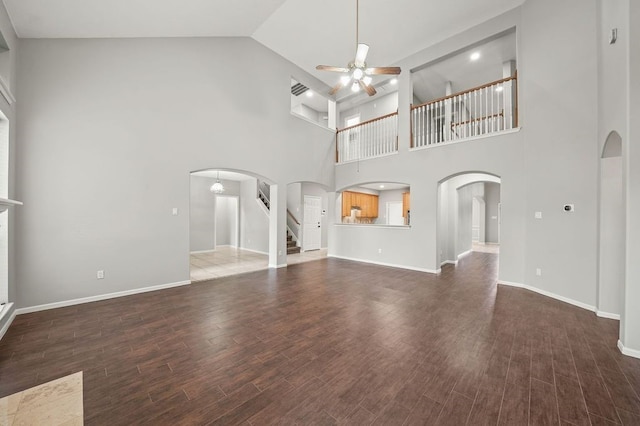 unfurnished living room with high vaulted ceiling, ceiling fan, and dark wood-type flooring