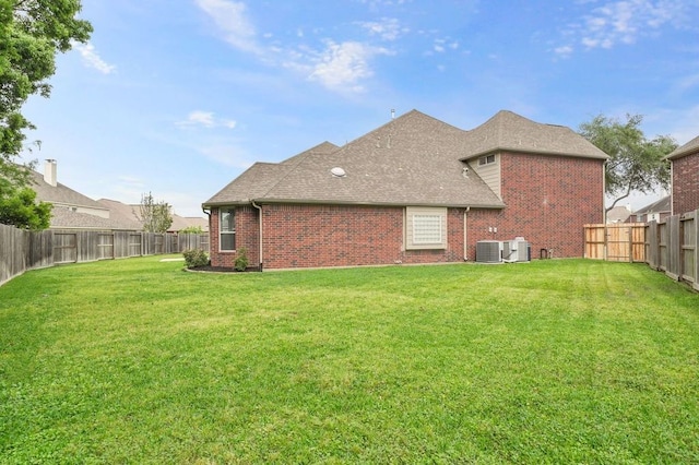 back of property with central AC unit and a lawn