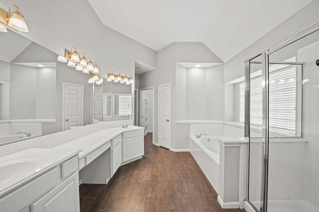 bathroom with vanity with extensive cabinet space, shower with separate bathtub, double sink, hardwood / wood-style floors, and vaulted ceiling