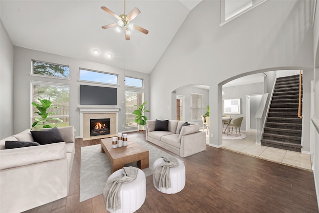 living room featuring high vaulted ceiling, ceiling fan, and light wood-type flooring