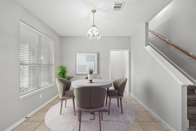 dining area featuring an inviting chandelier, a textured ceiling, and light tile floors